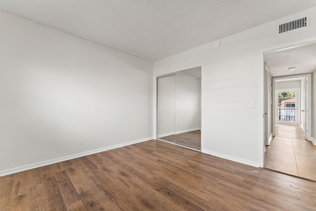 unfurnished bedroom featuring wood-type flooring and a closet