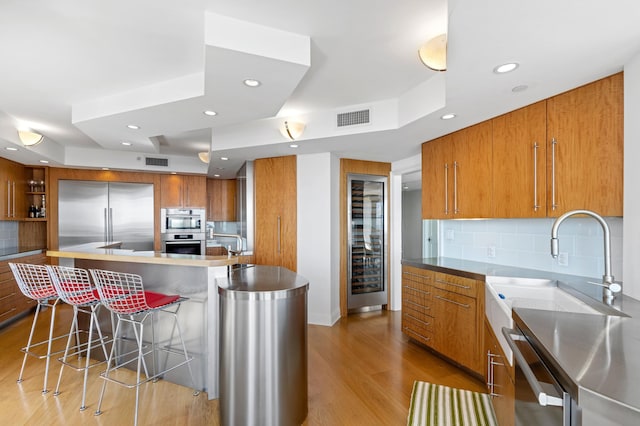 kitchen featuring sink, a kitchen bar, a large island, and built in fridge