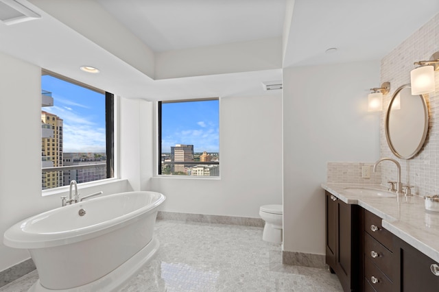 bathroom with a bathing tub, vanity, tasteful backsplash, tile patterned floors, and toilet