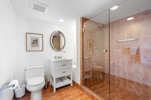 bathroom with a shower with door, vanity, tile patterned floors, and toilet