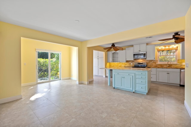 kitchen featuring decorative backsplash, sink, ceiling fan, white cabinetry, and appliances with stainless steel finishes