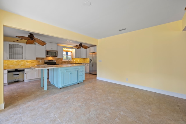 kitchen featuring stainless steel appliances, a breakfast bar area, a kitchen island, backsplash, and white cabinetry