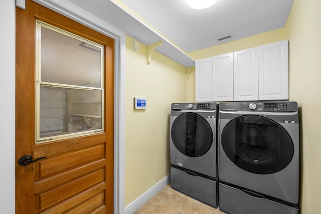 clothes washing area featuring cabinets and washer and dryer