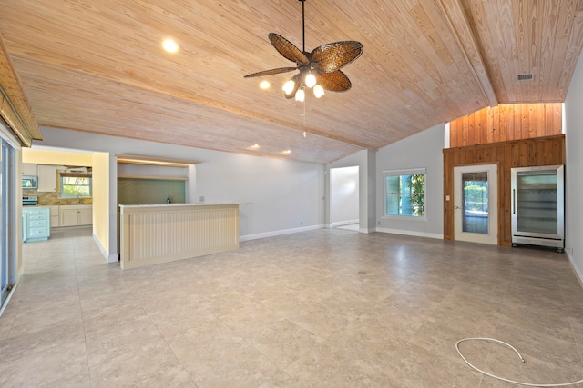 unfurnished living room featuring vaulted ceiling with beams, ceiling fan, and wood ceiling