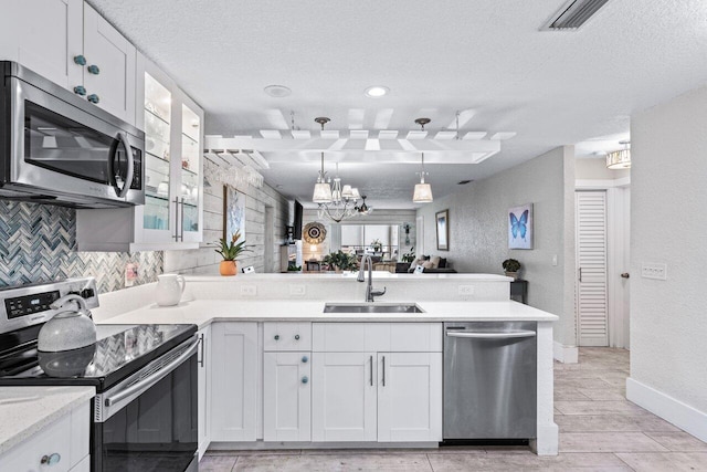 kitchen featuring white cabinetry, sink, hanging light fixtures, kitchen peninsula, and appliances with stainless steel finishes