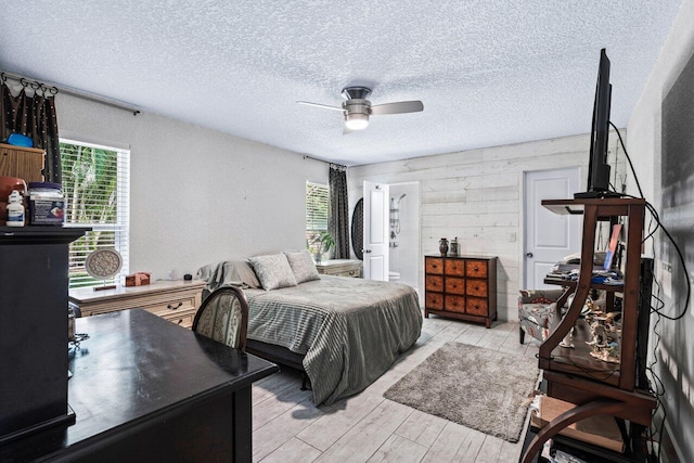 bedroom with a textured ceiling, light hardwood / wood-style flooring, and ceiling fan