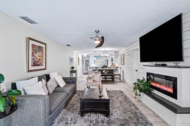 living room featuring ceiling fan, a textured ceiling, and light hardwood / wood-style flooring