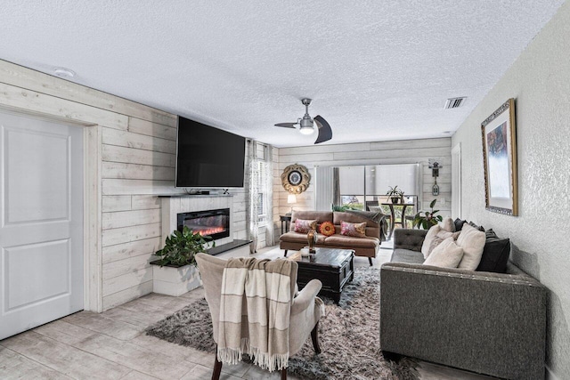 living room with a textured ceiling, ceiling fan, and wood walls