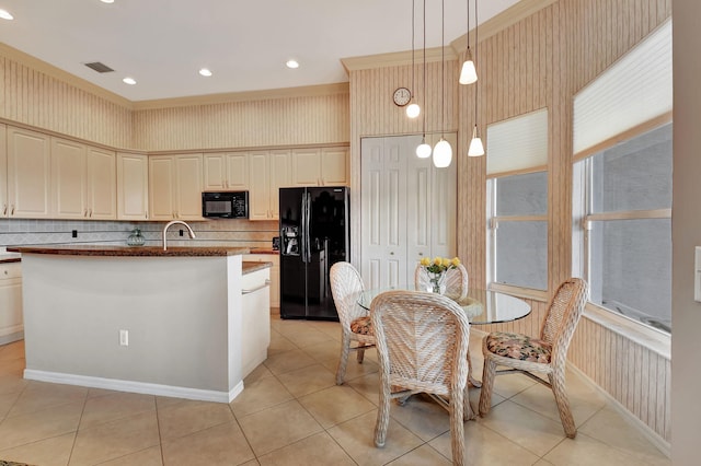 kitchen with an island with sink, pendant lighting, decorative backsplash, light tile patterned floors, and black appliances