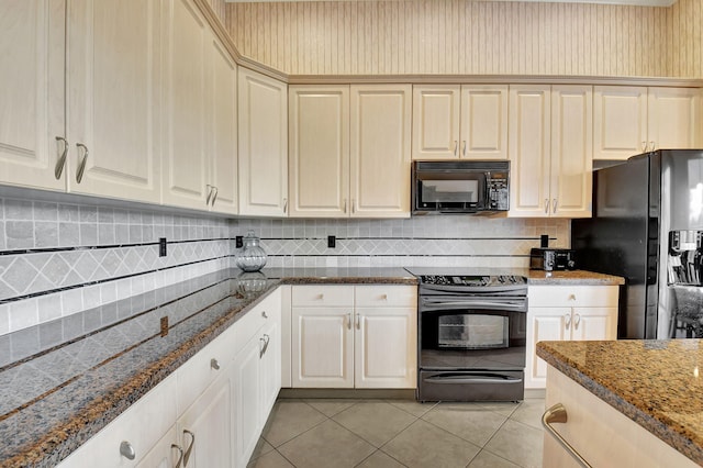 kitchen featuring backsplash, black appliances, dark stone countertops, light tile patterned floors, and cream cabinetry