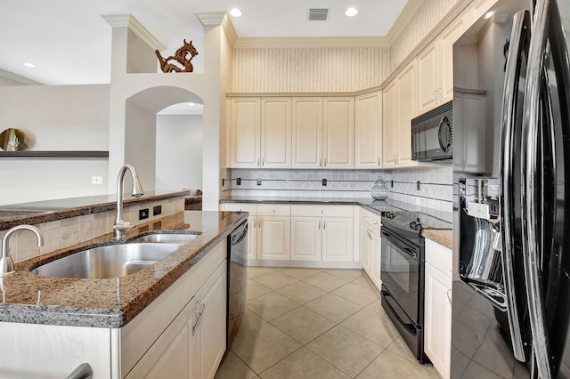 kitchen with backsplash, dark stone countertops, sink, and black appliances