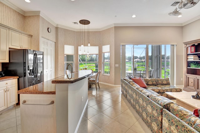 kitchen with a kitchen island with sink, black refrigerator with ice dispenser, decorative light fixtures, and ornamental molding