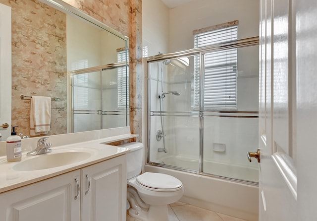 full bathroom featuring toilet, tile patterned flooring, vanity, and combined bath / shower with glass door