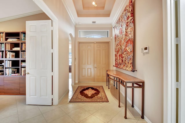 foyer entrance with a tray ceiling, crown molding, and light tile patterned flooring