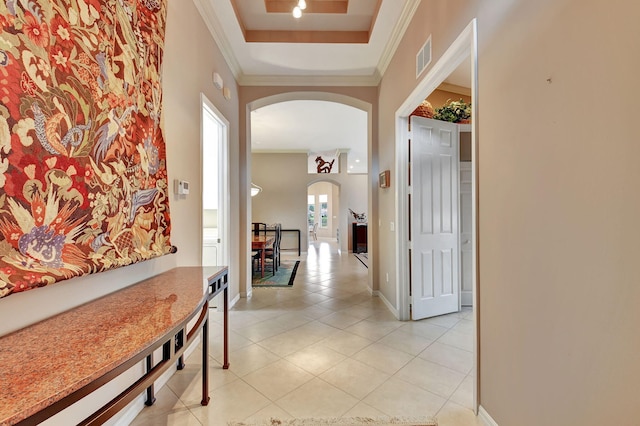 hallway with light tile patterned floors, a tray ceiling, and crown molding