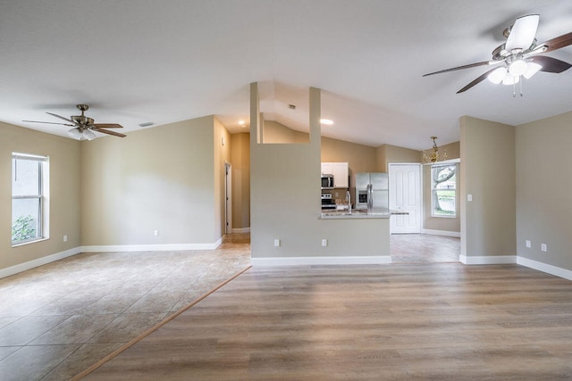 unfurnished living room with ceiling fan, light hardwood / wood-style flooring, vaulted ceiling, and sink