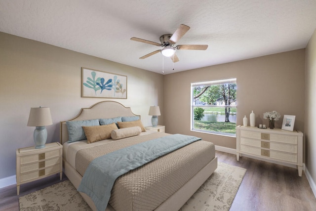 bedroom with ceiling fan, dark hardwood / wood-style floors, and a textured ceiling