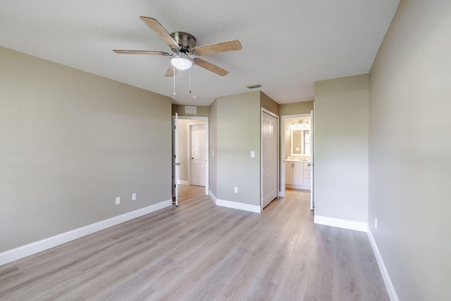 unfurnished bedroom featuring ceiling fan, light wood-type flooring, connected bathroom, and a closet