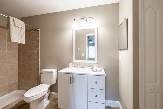 bathroom with vanity, ceiling fan, toilet, a textured ceiling, and tiled shower