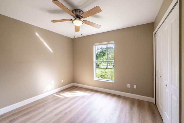 unfurnished bedroom with ceiling fan, a closet, and light hardwood / wood-style flooring