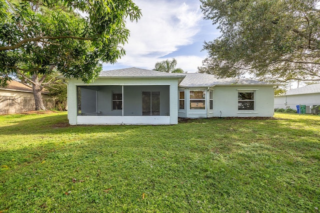 back of property with a lawn and a sunroom