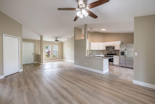 kitchen featuring kitchen peninsula, vaulted ceiling, appliances with stainless steel finishes, light hardwood / wood-style floors, and white cabinetry