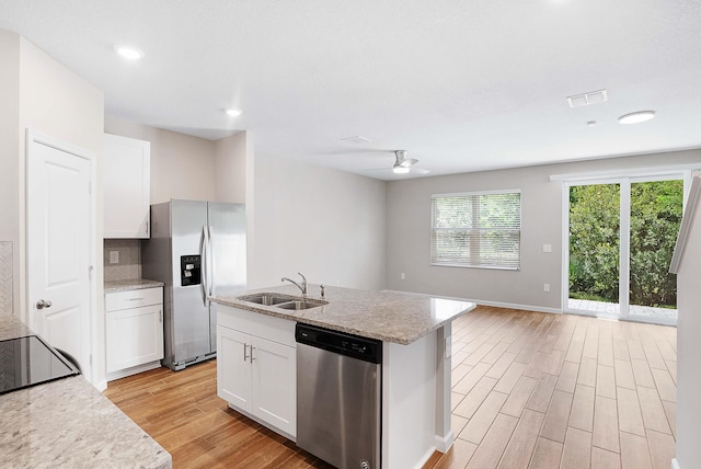 kitchen featuring appliances with stainless steel finishes, an island with sink, sink, white cabinets, and light hardwood / wood-style floors