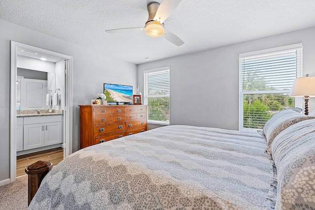 bedroom with sink, hardwood / wood-style flooring, ceiling fan, ensuite bathroom, and a textured ceiling