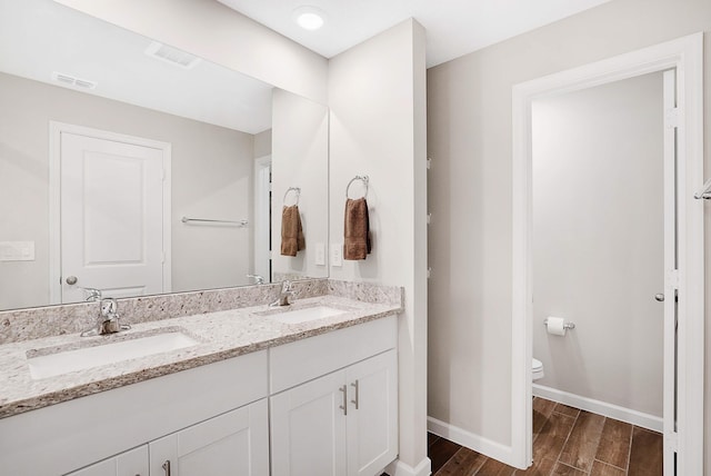 392 SE Sea Hunt Way, Stuart, FL 34994 - bathroom featuring baseboards, double vanity, wood finished floors, and toilet
