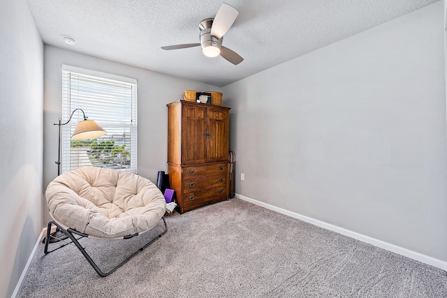 living area featuring ceiling fan, carpet floors, and a textured ceiling