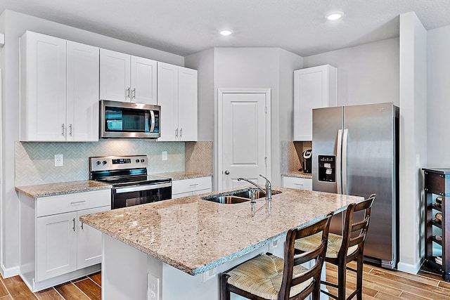 392 SE Sea Hunt Way, Stuart, FL 34994 - kitchen with appliances with stainless steel finishes, wood finish floors, a sink, a breakfast bar area, and recessed lighting