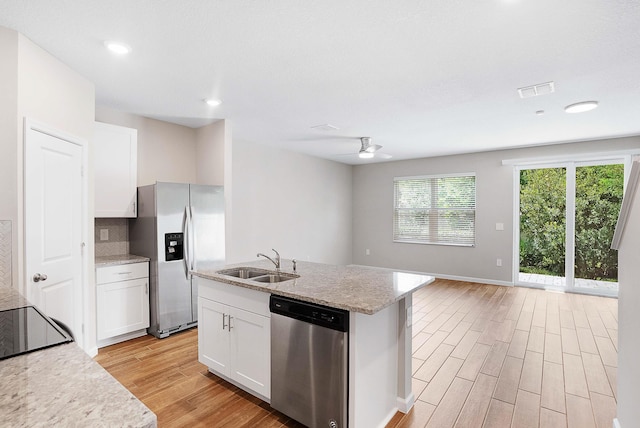 392 SE Sea Hunt Way, Stuart, FL 34994 - kitchen with stainless steel appliances, a sink, light wood finished floors, white cabinets, and a kitchen island with sink