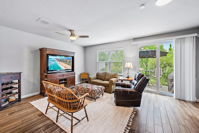 living room with ceiling fan, hardwood / wood-style floors, and a textured ceiling