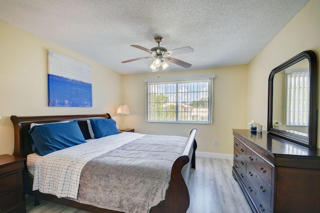 bedroom featuring light hardwood / wood-style floors, ceiling fan, and a textured ceiling