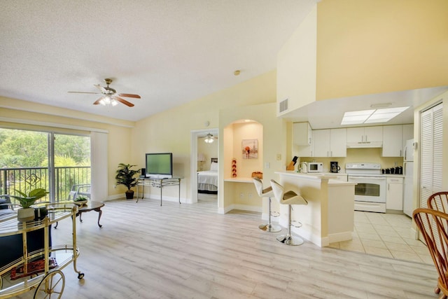 kitchen featuring white cabinetry, white appliances, a kitchen bar, kitchen peninsula, and light hardwood / wood-style flooring