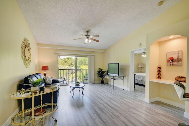 living room with light hardwood / wood-style flooring, a textured ceiling, and ceiling fan