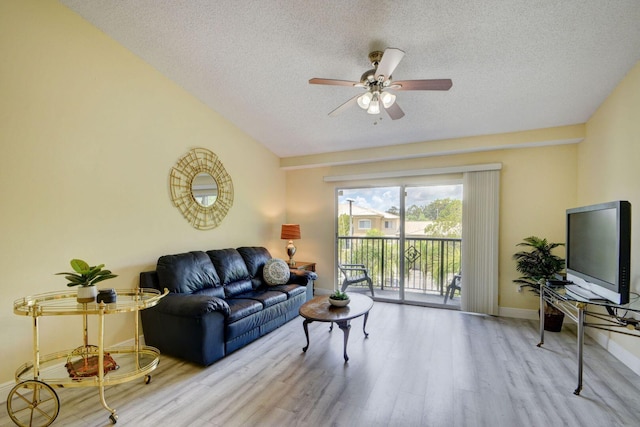 living room with ceiling fan, a textured ceiling, and light wood-type flooring