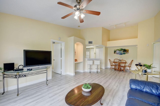 living room with ceiling fan, a textured ceiling, track lighting, and light wood-type flooring