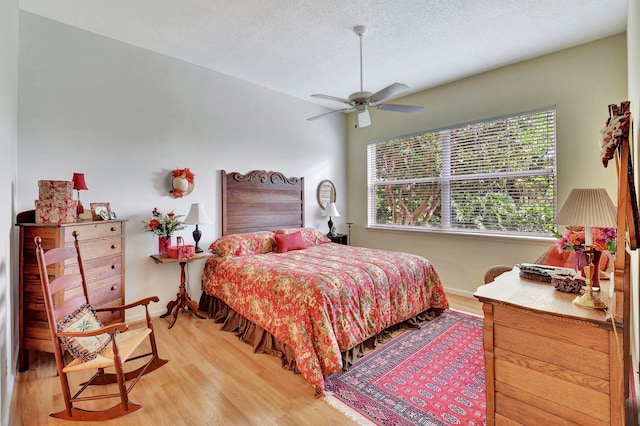 bedroom with ceiling fan, light hardwood / wood-style flooring, and a textured ceiling