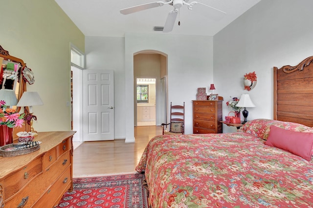 bedroom with connected bathroom, ceiling fan, and light hardwood / wood-style flooring