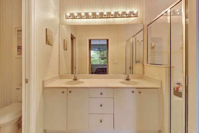 bathroom with a shower with door, vanity, and toilet