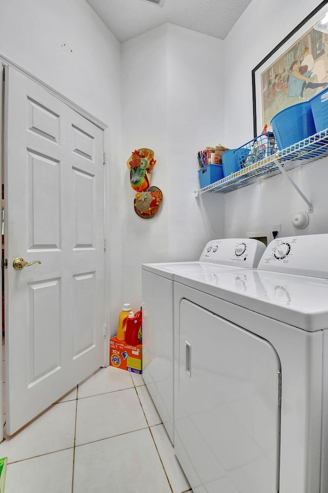 laundry room with washing machine and clothes dryer and light tile patterned floors