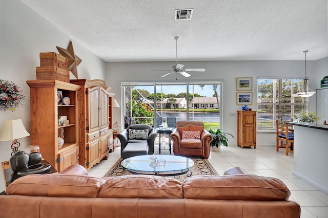 tiled living room featuring a textured ceiling, ceiling fan, and a wealth of natural light