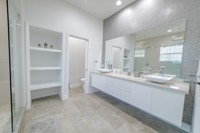 bathroom with built in shelves, toilet, vanity, and walk in shower