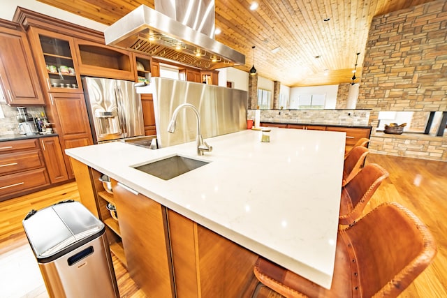 kitchen with stainless steel fridge, light wood-type flooring, tasteful backsplash, wall chimney exhaust hood, and sink