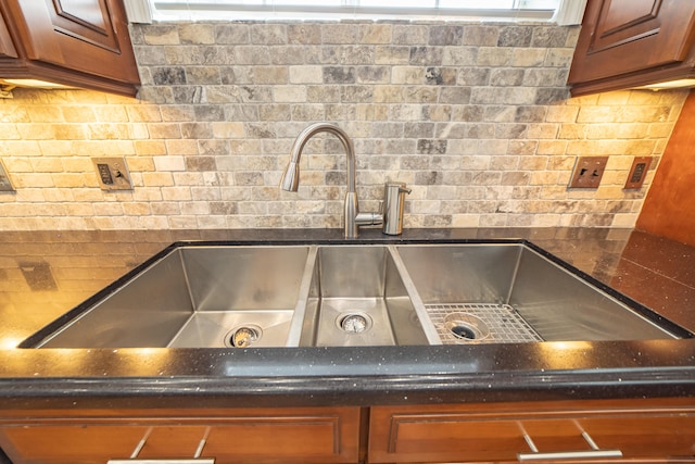 room details with decorative backsplash, dark stone countertops, and sink