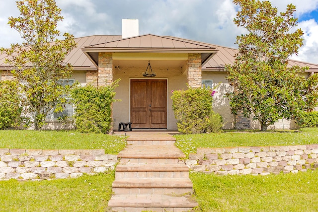 view of exterior entry with covered porch and a lawn