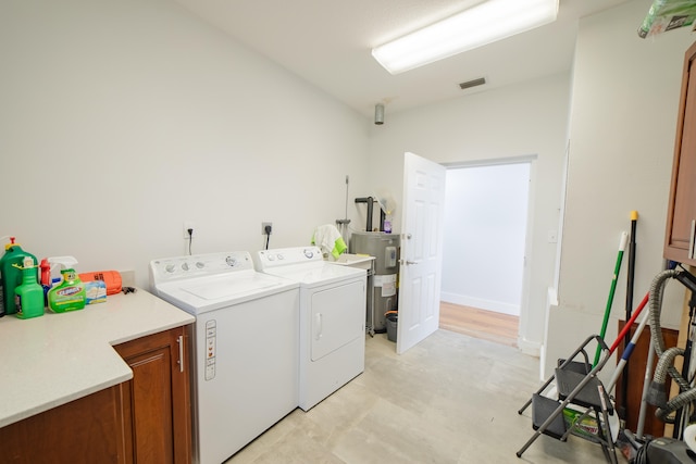 laundry room with water heater, cabinets, and independent washer and dryer