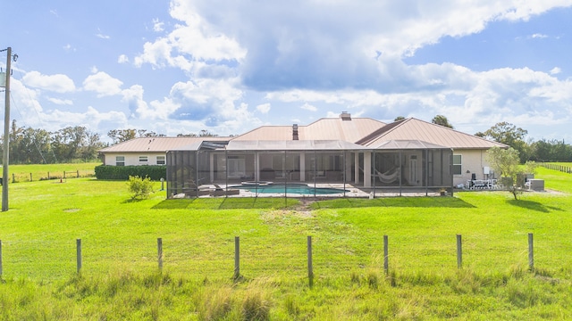 rear view of house featuring a lawn, glass enclosure, and a patio