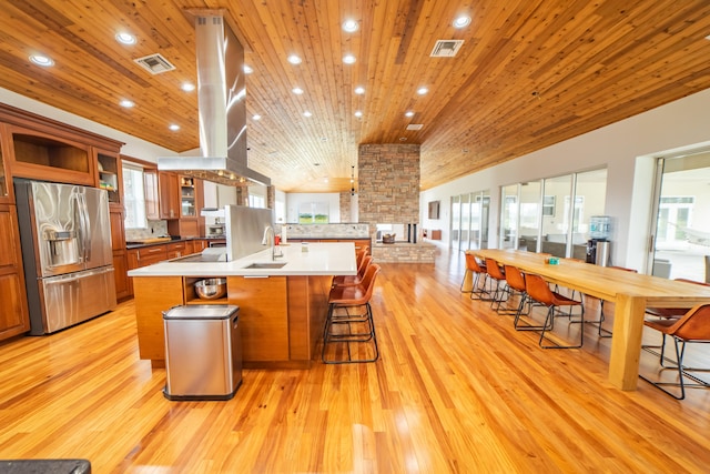 kitchen featuring a breakfast bar, stainless steel fridge, light hardwood / wood-style floors, and wood ceiling